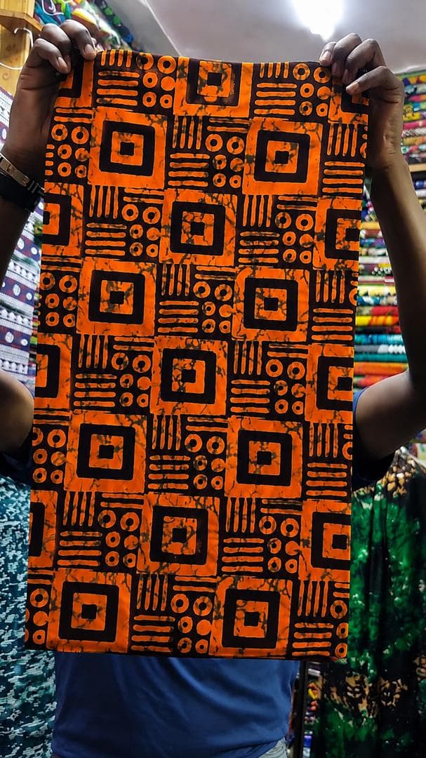 Orange and black block-print batik — styled as a tailored blazer — the fabric in stock at Zion Vitenge Centre
